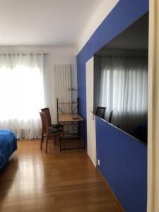a bedroom with a blue wall and a bed and a desk at maison blanche in Eymet