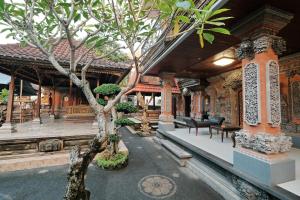 a house with a tree in front of a building at Sumantra Guest House in Ubud