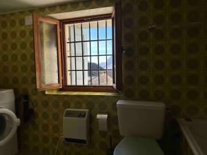 a bathroom with a toilet and a window at Waterfall House - Art and Design, Ski, Hike, Swim in Mesocco +80 photos