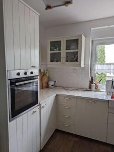 a white kitchen with white cabinets and an oven at Haus in der Nähe vom See in Markranstädt