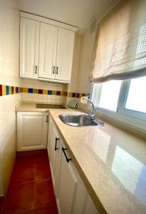 eine kleine Küche mit einem Waschbecken und einem Fenster in der Unterkunft MyChoice Dos Mares by Bossh! Apartments in Rota