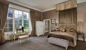 a bedroom with a bed and a chair and windows at Mar Hall Golf & Spa Resort in Bishopton