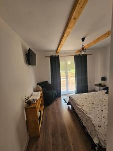 a bedroom with a bed and a tv and a window at Casa Denis & Kevin in Petrila