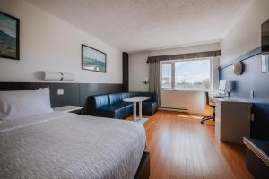 Habitación de hotel con cama y escritorio en Le Dauphin Montréal-Longueuil, en Longueuil