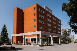 duży pomarańczowy budynek z parkingiem w obiekcie Le Dauphin Montréal-Longueuil w mieście Longueuil