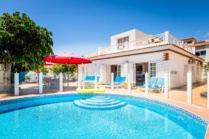 a swimming pool with an umbrella and chairs and a house at Villa Lory in Callao Salvaje