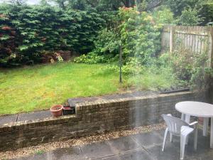 a patio with a table and chairs and a grass yard at Lokiladdich in Bearsden