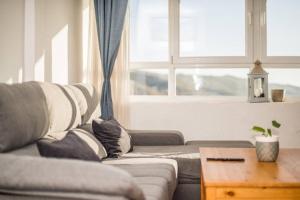 uma sala de estar com um sofá e duas janelas em The Apartment Luminoso duplex en sierra nevada em Sierra Nevada