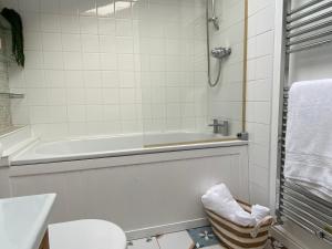 a bathroom with a tub and a toilet and a sink at Seaglass Cottage Mumbles in Oystermouth