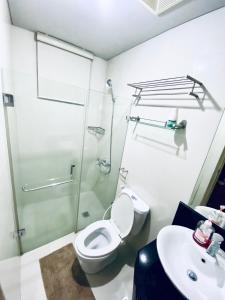 La salle de bains est pourvue d'une douche, de toilettes et d'un lavabo. dans l'établissement Norico's 1Bedroom @ One Palmtree Villas, à Manille