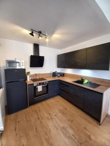 a kitchen with a black refrigerator and wooden floors at Coeur d'Uzès in Uzès