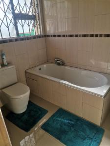 a bathroom with a tub and a toilet and rugs at Phakathi Lifestyle Village Umnini in Amanzimtoti