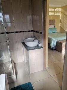 a bathroom with a sink and a bed at Phakathi Lifestyle Village Umnini in Amanzimtoti