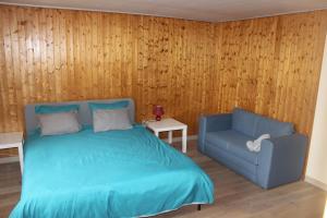 1 dormitorio con 1 cama azul y 1 silla en Chez Ginette et Jean-François, en Le Chenit