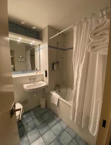 La salle de bains est pourvue d'une baignoire, d'un lavabo et d'une douche. dans l'établissement Kyriad Le Blanc-Mesnil, au Blanc-Mesnil