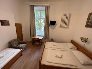 a room with two beds and a chair and a window at Hotel-Pension Spree in Berlin