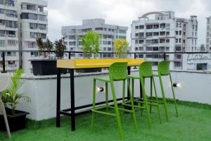 ein gelber Tisch und vier grüne Stühle auf dem Balkon in der Unterkunft Hotel Royal Accord in Surat