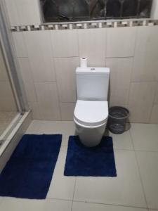 a bathroom with a toilet and two blue rugs at Phakathi Lifestyle Village Umnini in Amanzimtoti