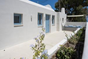 uma casa branca com uma porta azul e flores em Tholaki luxury home em Kamari