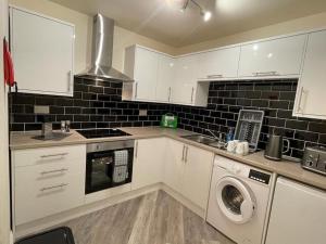 a kitchen with white cabinets and a sink and a washer at Lovely 2 bedroom apartment in Fleetwood in Fleetwood