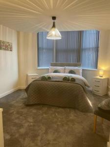 a bedroom with a large bed and a chandelier at Lovely 2 bedroom apartment in Fleetwood in Fleetwood