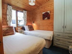 um quarto com 2 camas num chalé de madeira em Elm Lodge em Keswick