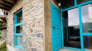 a blue door and windows on a stone building at Hillhouse Hunza in Hunza