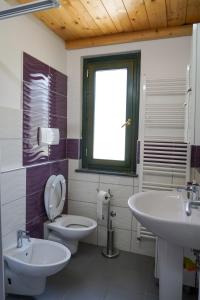 a bathroom with two sinks and a toilet and a window at Villetta San Martino in Torraca