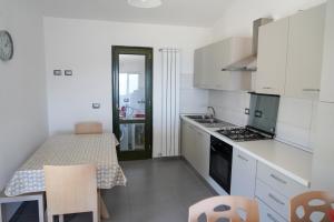 a white kitchen with a table and a table and chairs at Villetta San Martino in Torraca +13 photos