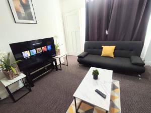 sala de estar con sofá y TV en Cozy Apartment en Cambois