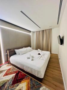 a bedroom with a large white bed with a rug at Green Coast Resort & Residences 94 in Palasë