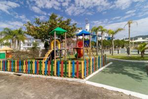 um parque infantil num parque com uma cerca colorida em Apto com sacada a poucos metros da praia VIN202 em Florianópolis