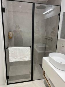 een vrouw die achter een glazen douche in een badkamer staat bij Simply with love-haifa in Haifa