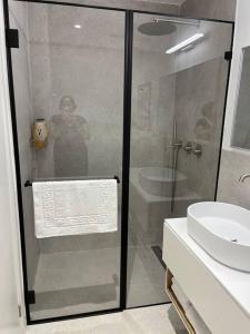 a woman standing behind a glass shower in a bathroom at Simply with love-haifa in Haifa +10 photos
