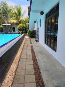 a walkway next to a swimming pool next to a house at Villa Tangalle Lagoon in Tangalle
