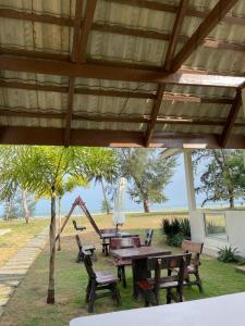 einen Picknicktisch und Stühle unter einem Pavillon mit Spielplatz in der Unterkunft DamaiiKu in Cherating
