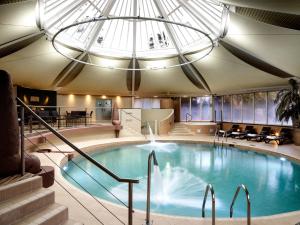 a large swimming pool with a skylight in a building at The Vineyard Hotel & Spa in Newbury