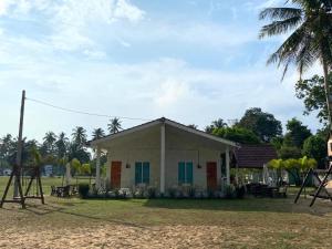 een klein wit gebouw met blauwe deuren en een speeltuin bij DamaiiKu in Cherating