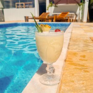 a drink in a glass next to a swimming pool at Éden Pampulha - Hotel Coworking in Belo Horizonte