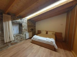 ein Schlafzimmer mit einem Bett in einem Zimmer mit einer Steinmauer in der Unterkunft Casa da Marquinhas - Turismo Rural 