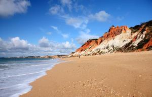 uma praia de areia com falésias brancas e o oceano em HÔTELS &ASPA em Estoril