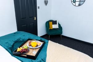 a tray of fruit and orange juice on a bed at Perfect for Long Stay Workers Leisure Families in Wolverhampton