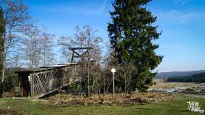 uma ponte velha num campo com uma árvore em La chambre d’auguste em Saint-Hubert