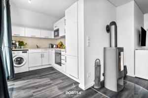 a kitchen with white cabinets and a washer and dryer at Ostseeloft in Olpenitz
