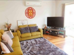 un soggiorno con divano giallo e TV a schermo piatto di Tina house a Springvale