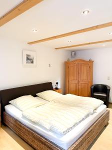 a large bed in a bedroom with a black chair at Ferienapartment Opitz - Zugspitzregion in Ohlstadt