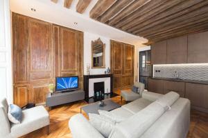 a living room with a couch and a tv at Contrevents in Paris +3 photos