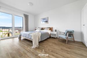a white bedroom with a bed and a chair at Villa Dein Zuhause am Meer in Büsum