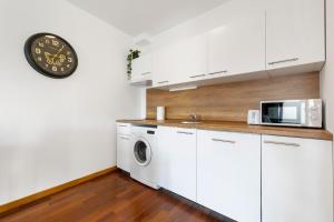 een keuken met een wasmachine en droger en een klok bij Urban Elegance Retreat in Bratislava