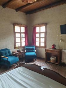 een slaapkamer met blauwe stoelen, een bed en ramen bij Avangart Hotel in Avanos